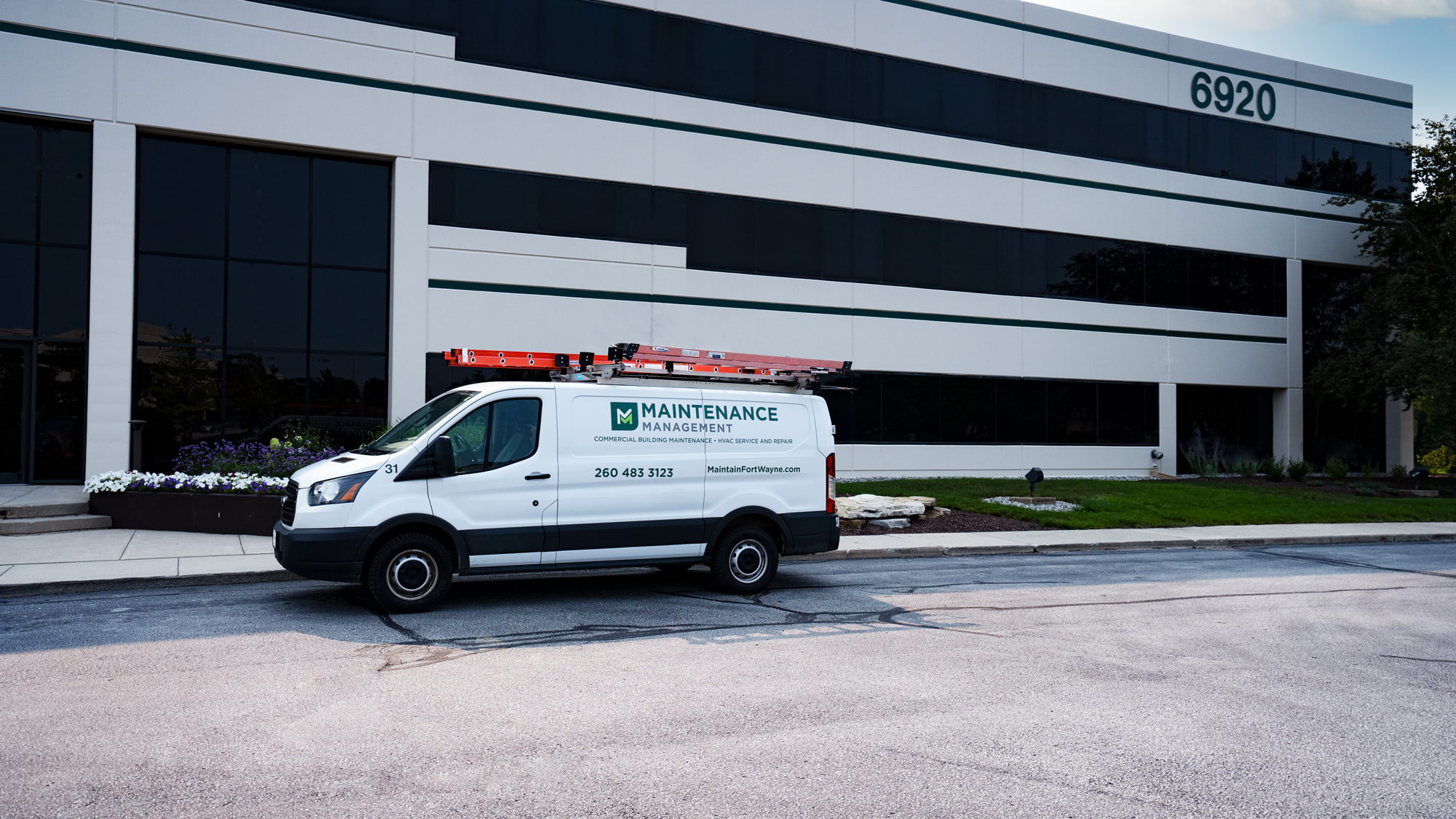 Maintenance Management outsourcing maintenance and HVAC service van in front of multi-tenant office building.